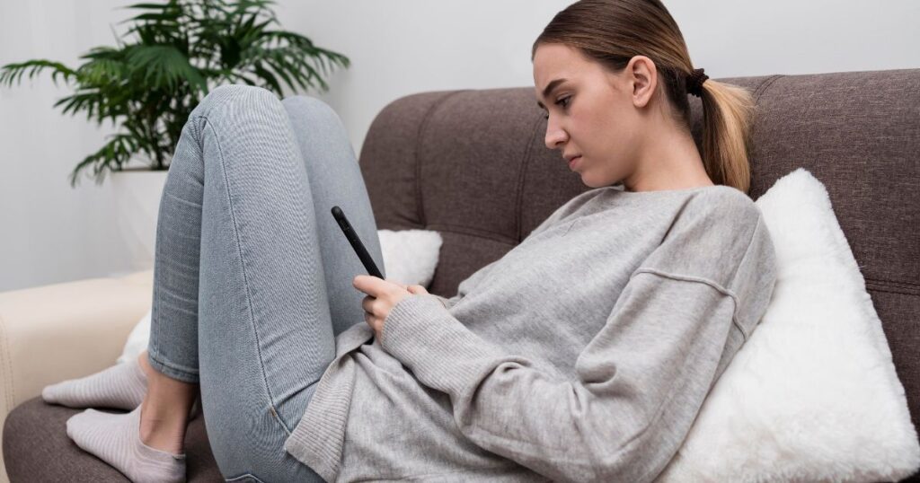 Nő kanapén görget a telefonján – a FOMO a közösségi médiában esti valósága